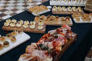 Table de buffet garnie d'assiettes d'apéritifs variés: charcuterie, œufs mimosa au caviar, mini-tartelettes salées et canapés.