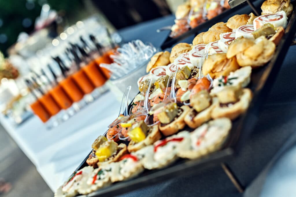 Plateau de traiteur avec assortiment élégant de canapés salés, roulés charcutiers et mini-quiches. Buffet événementiel.
