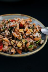 Tartare de saumon frais et coloré avec des dés d'oignon rouge, aneth, graines noires et arachides, servi dans un bol.