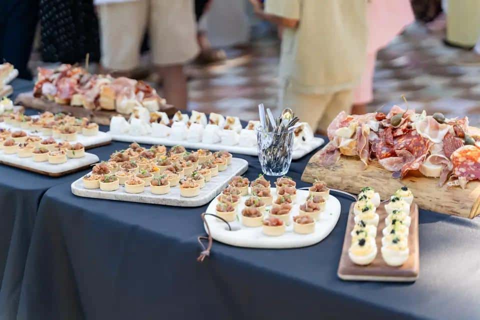 Table de buffet garnie d'amuse-bouches variés: mini-tartes, planches de charcuterie, fromages et œufs mimosa au caviar. Réception.