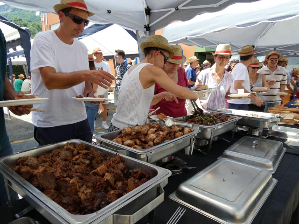 Buffet Traiteur Extérieur : Viandes Grillées et Fête Convives en chapeau de paille se servant de la viande à un buffet extérieur convivial.